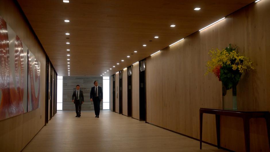 Benny and Bull walk down the hallway after getting off the elevator.