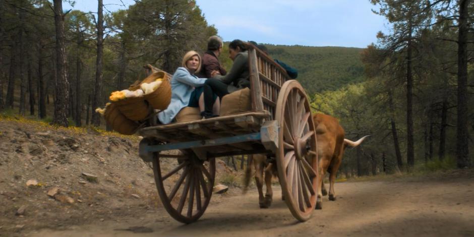 The Doctor glances back from the back of the cart as it drives away with her and her friends.