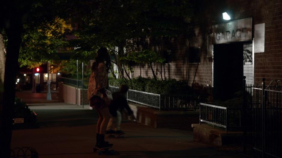 Liza and Josh skate down the sidewalk away from the house.