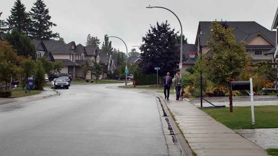 James walks next to Tom as he walks his dog down the street.