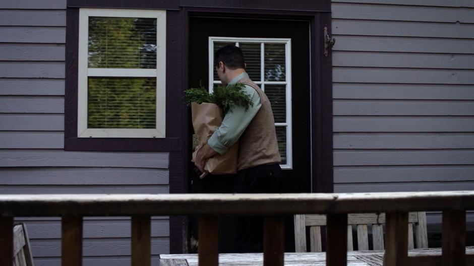 Back Lockwood opens the back door of his home while holding the bag of groceries.