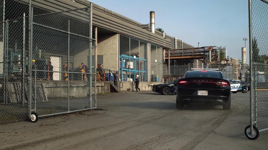 The police pull up outside the factory under siege.