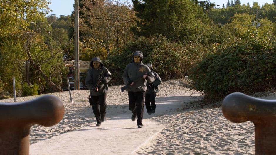 Three members of the Children of Liberty run down the path towards the dock.