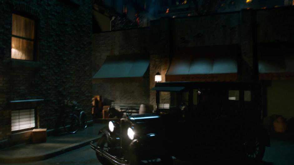 A car drives through the streets of Paris at night.