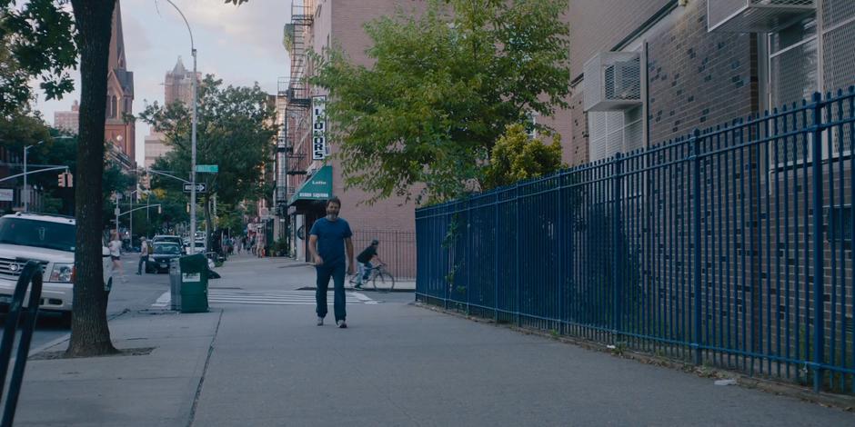 Frank walks down the sidewalk to the monument.