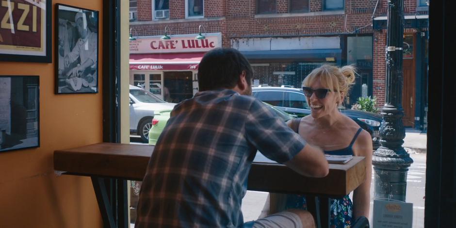 Leslie gets Frank's attention as he is sitting in a window seat filling out the application.