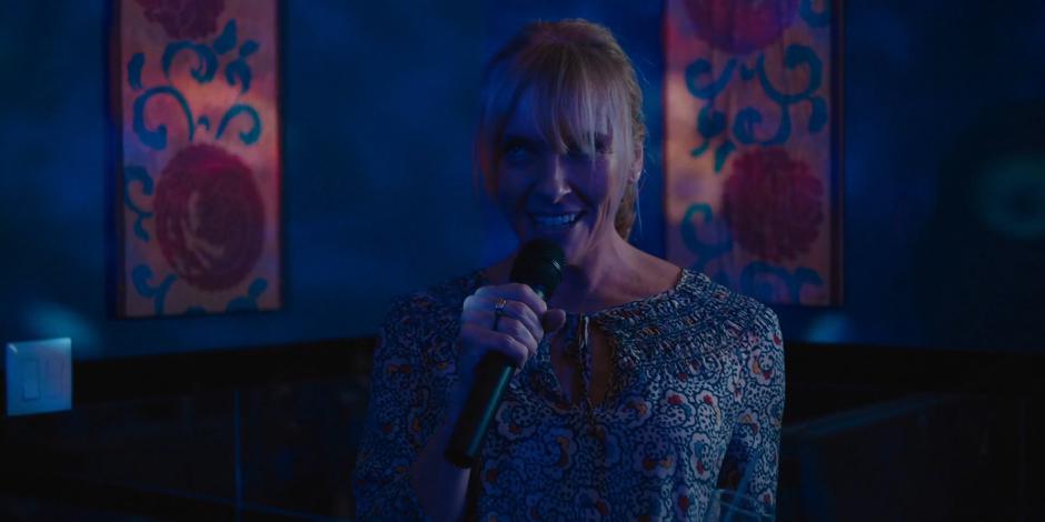 Leslie sings karaoke in a dimly lit room.