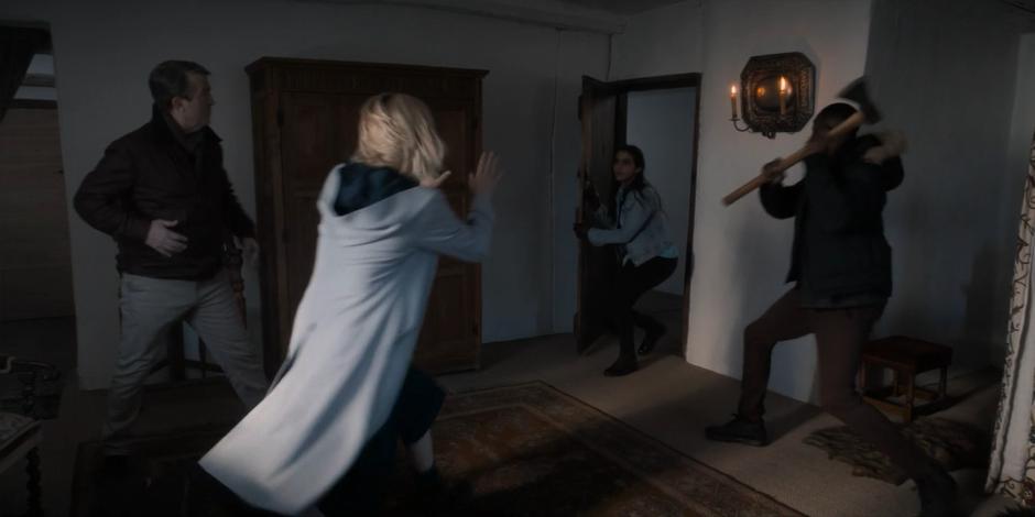 Graham and the Doctor turn to the door as Yasmin bursts inside while Ryan holds up the ax.