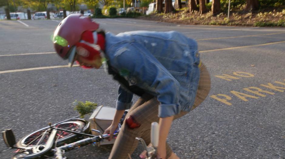 Mona lifts up her bike after being knocked to the ground.