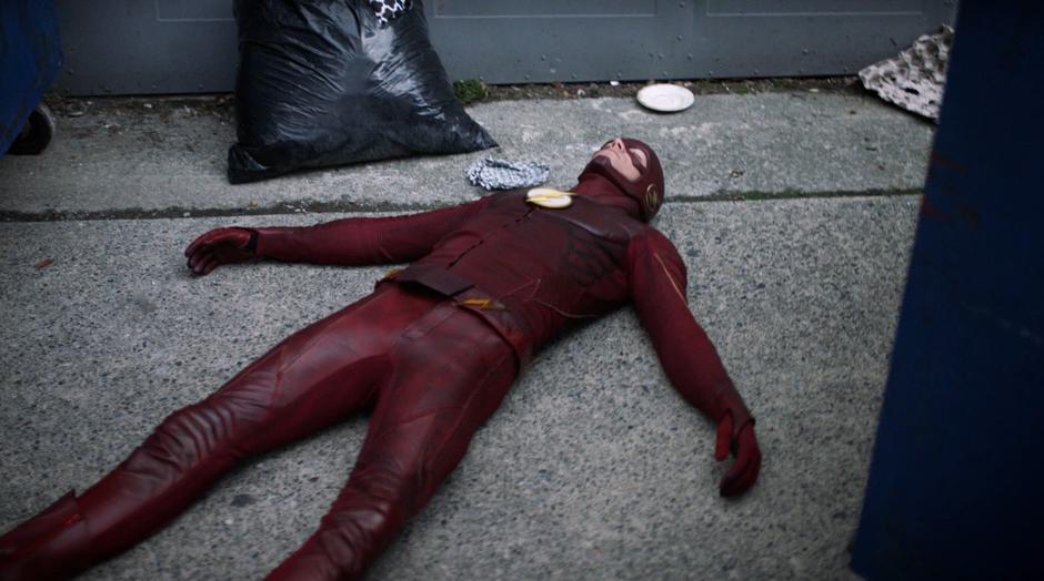 An earlier version of Barry in the Flash suit lies unconscious in the alley.