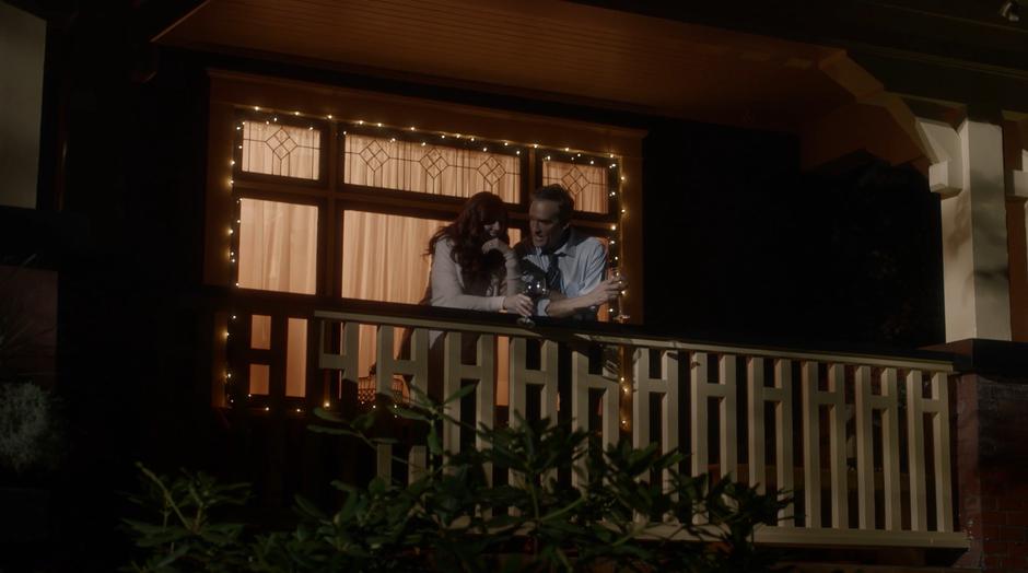 Nora and Henry Allen talk and drink wine on the porch of their home.