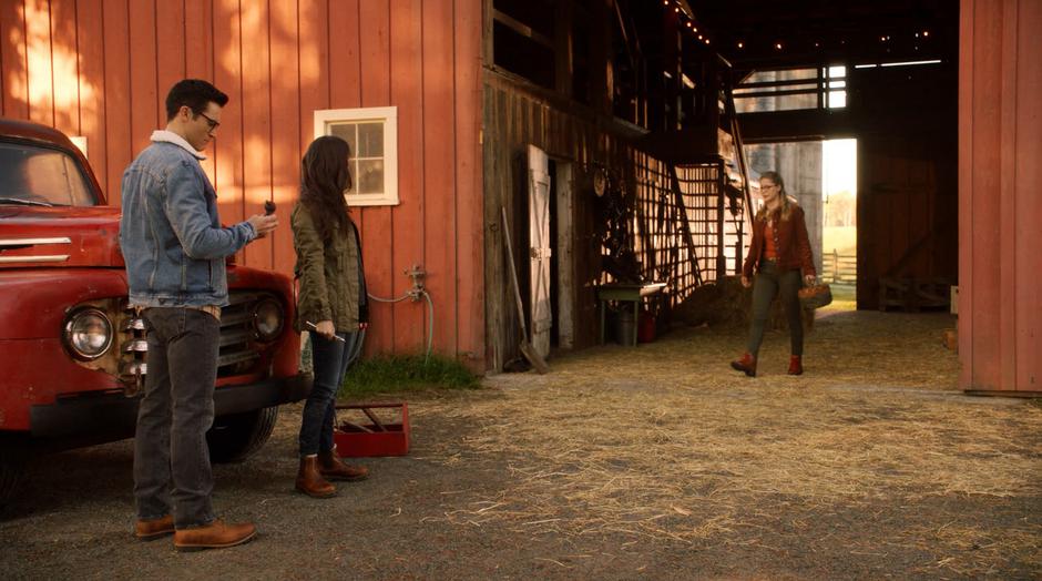 Kara walks out of the barn to where Clark and Lois are finishing their work on the truck.