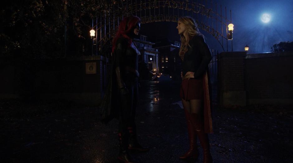 Kara stops after the others leave to flirt with Kate Kane outside the gate.