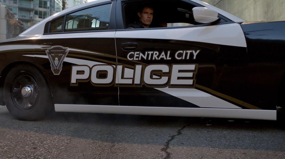 The Central City Police car slides to a stop in front of Barry and Oliver.