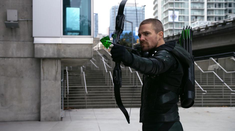 Oliver holds a kryptonite arrow at Deegan.