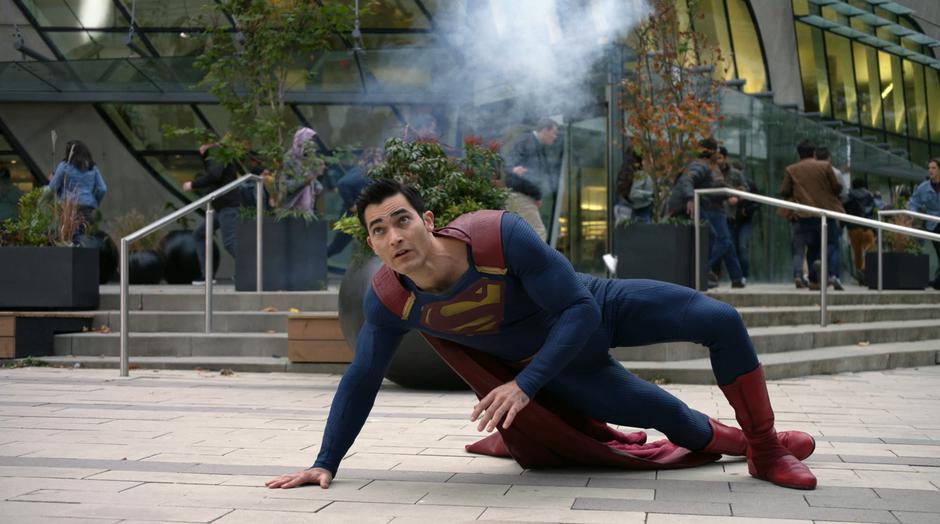 Clark climbs off the ground and tries to get to Lois as she falls.