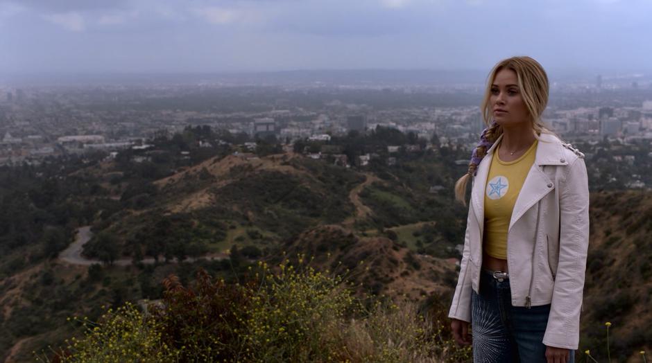 Karolina turns towards Jonah on top of the hill.