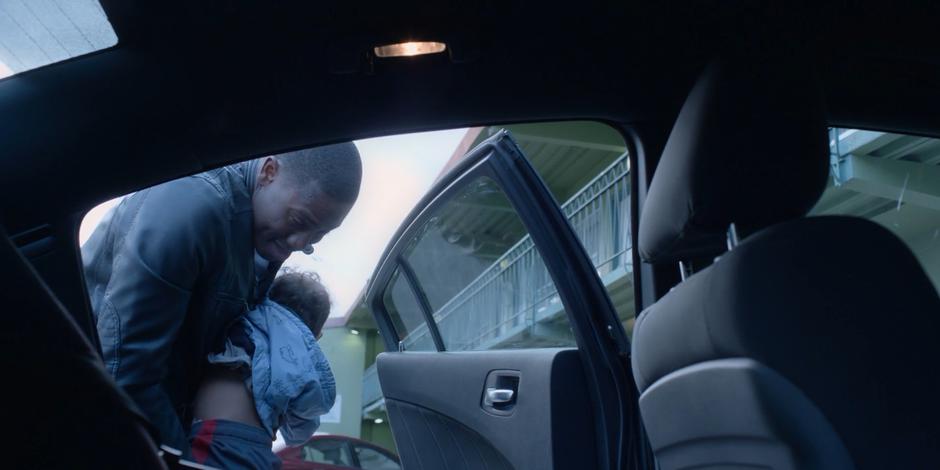 Jeff settles his son into the back seat of his car.