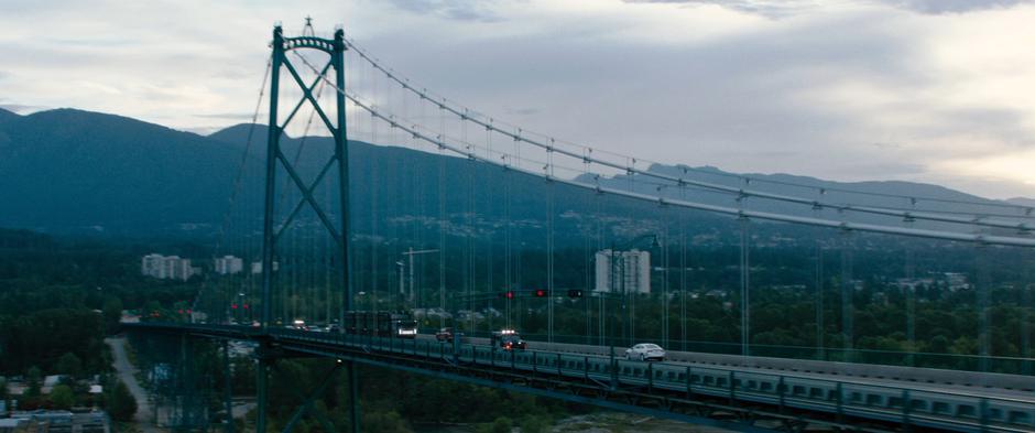 The prisoner transport drives across the bridge surrouned by cars with lights shining.