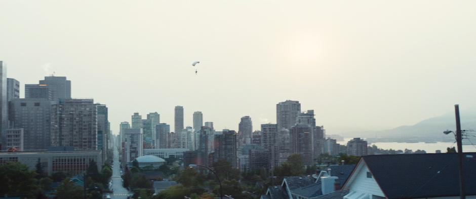 Shatterstar floats down towards the city on his parachute.