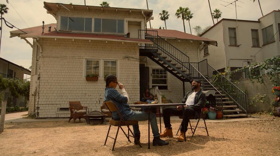 Alex talks to Darius while they play dominoes in the back yard.