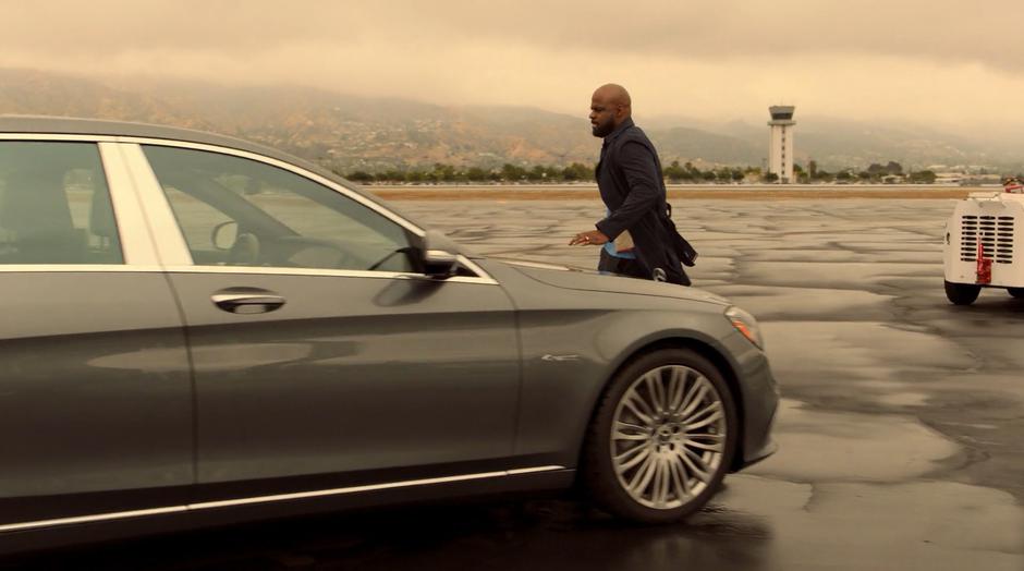 Geoffrey runs around his car to the driver-side door.