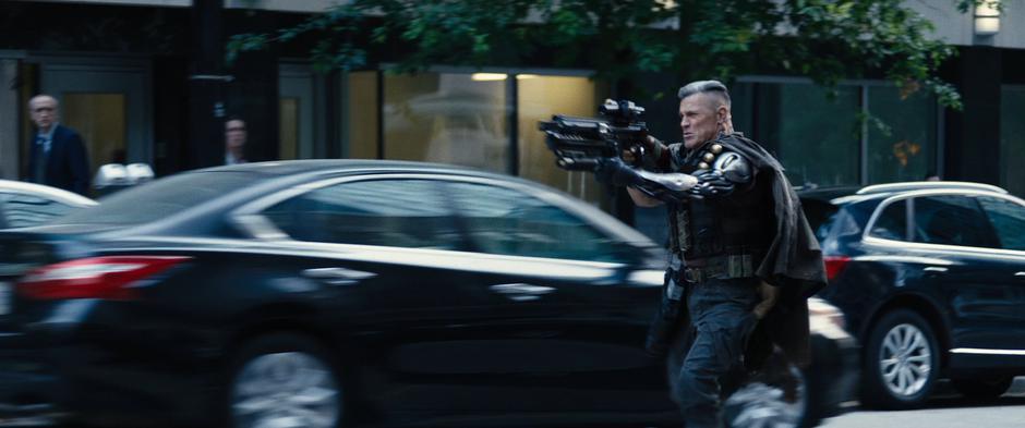 Cable raises his gun to fire at the convoy.