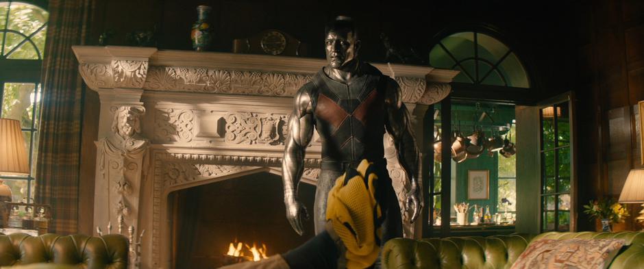 Colossus goes into the living room to talk to Wade as he holds up the X-Men trainee shirt.