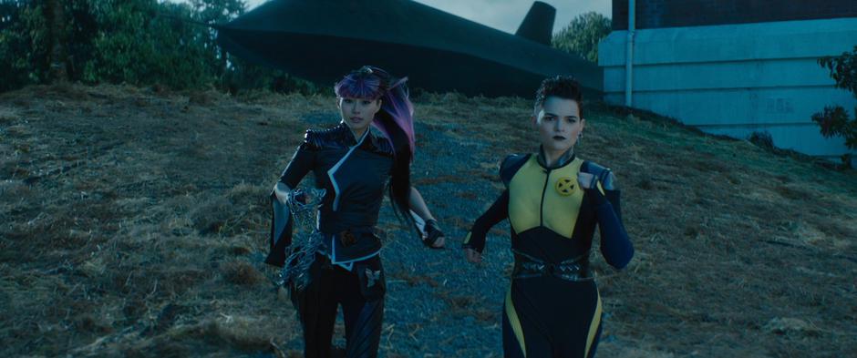 Yukio and Negasonic Teenage Warhead run down the hill from the Blackbird towards the battle.