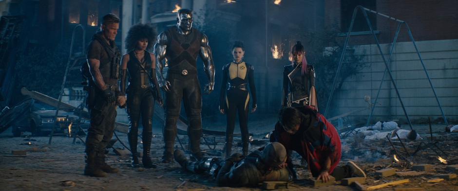 Cable, Domino, Colossus, Negasonic Teenage Warhead, and Yukio look down as Russell kneels over a dying Wade.