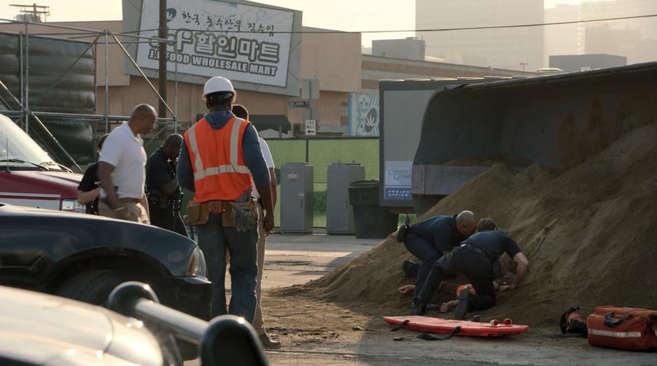 Paramedics dig the injured worker out of the overturned pile of dirt.