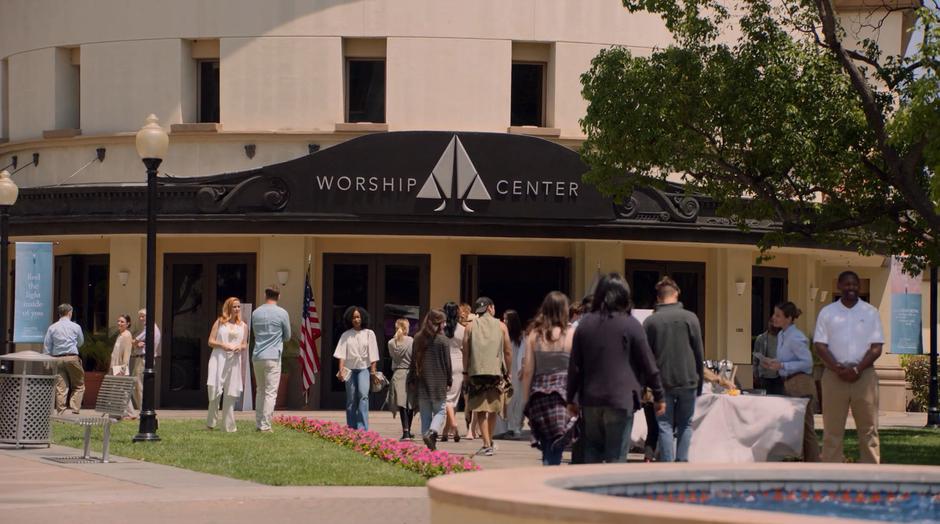 Frank turns around to talk to Leslie while members of the church welcome homeless kids.