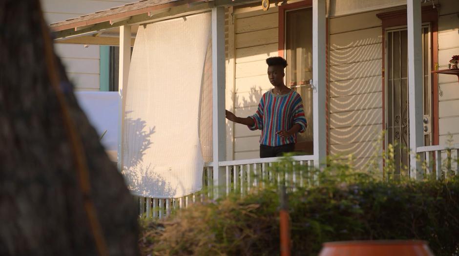 A young woman watches from her house across the street.