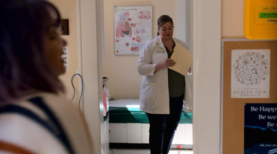 The school nurse pulls out Gert's records while Gert stands nervously.