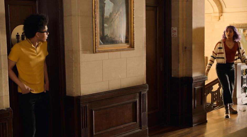 Alex stands guard at the bathroom door as Gert runs up the stairs looking for them.