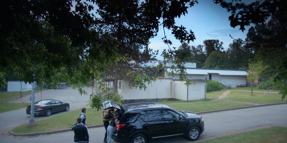 Trevor and Grant watch Jeff drive up while Carly and Marcy grab their gear from the back of their SUV.