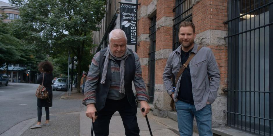 David smiles at James Edward Bailey while walking with him down the sidewalk.