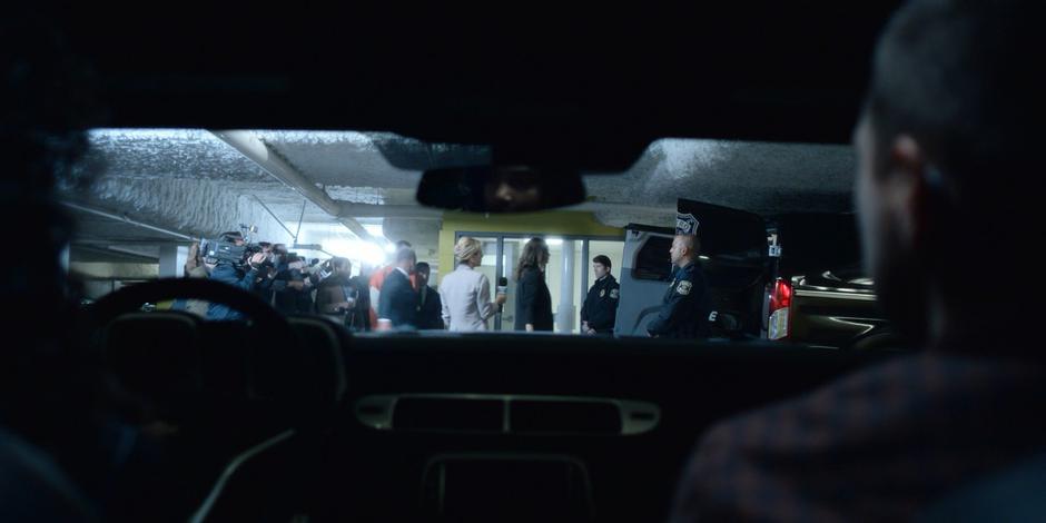 Carly and Trevor watch Joanne lead Andrew Graham to the van from inside their car.