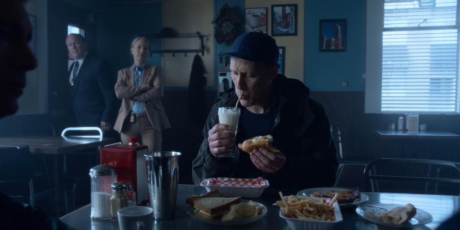 Andrew Graham takes a big drink from his milkshake while the two police detectives wait by the door.