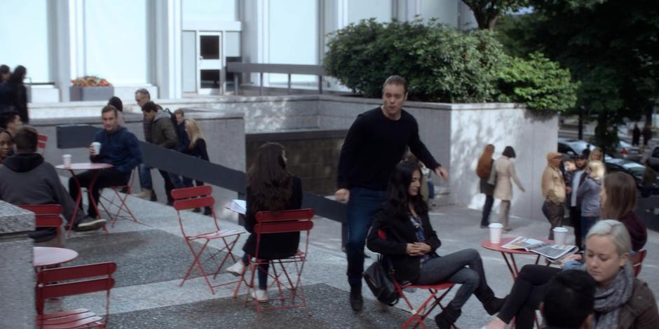 Philip runs between tables where people are drinking coffee.