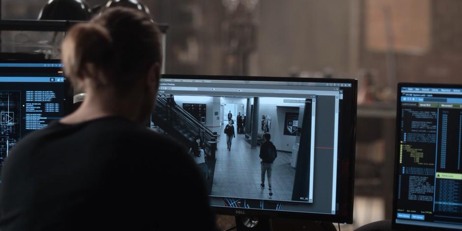 Philip watches security footage of students walking through the hallway at the university.