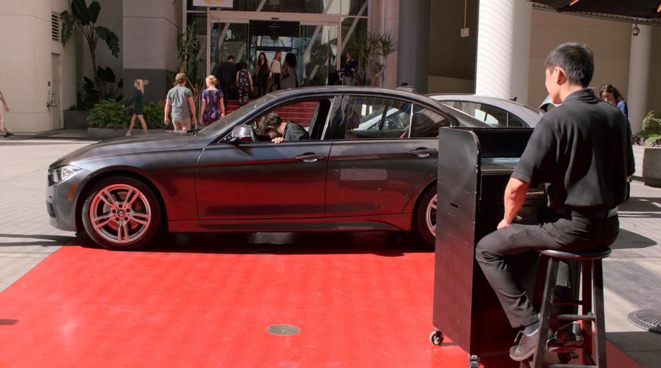 A valet roots around inside a car at the valet stand.