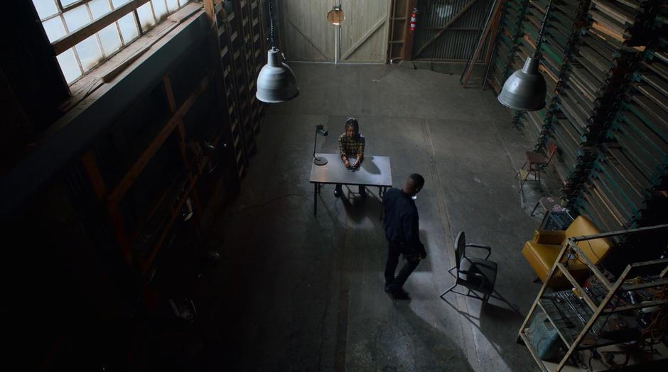 AWOL walks around the table where Livvie is handcuffed.