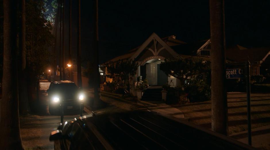 Two police SUVs converge on the house at night.