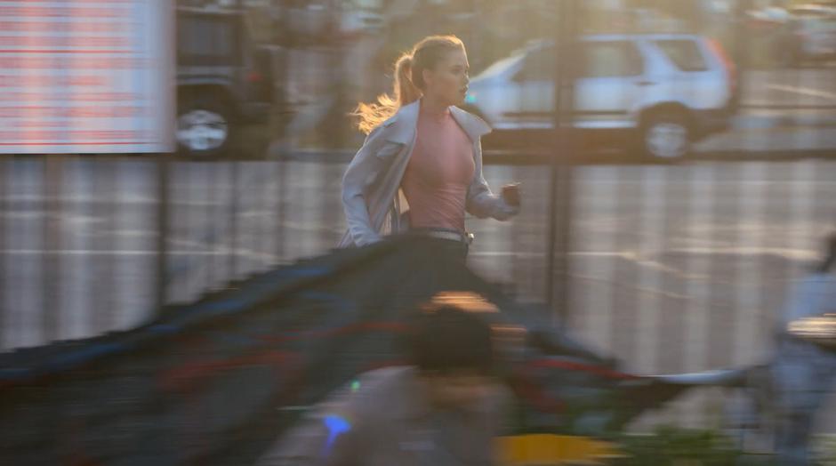 Karolina runs down the sidewalk towards the warehouse.