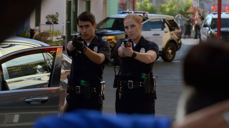 Two police officers hold their guns on the Wilders.