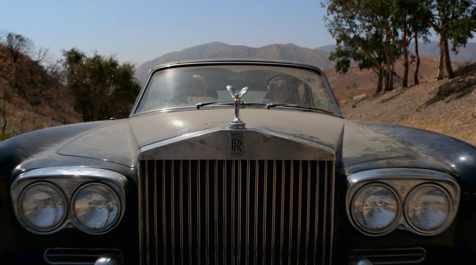 Karolina pulls the car to a stop on the road outside the compound.