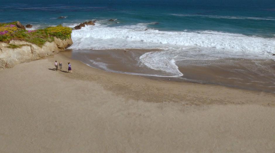 Janet leads Michael and Eleanor down the beach.