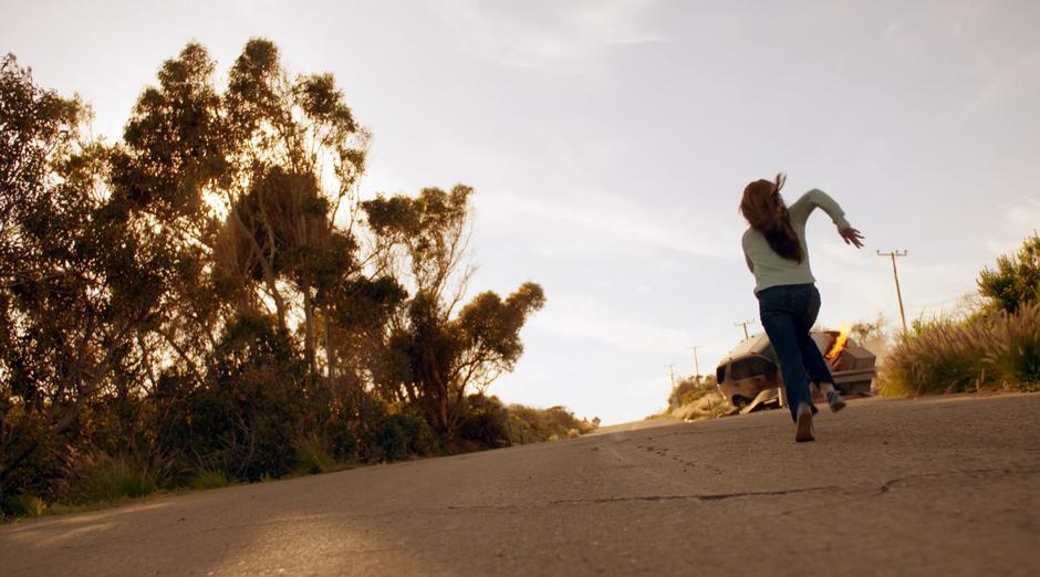 Young Kara runs up the street towards the crashed and burning car.