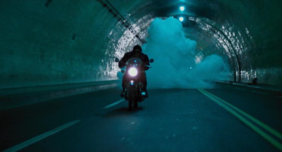 The Terminator rides his motorcycle down the tunnel as a pipe bomb explodes behind him.